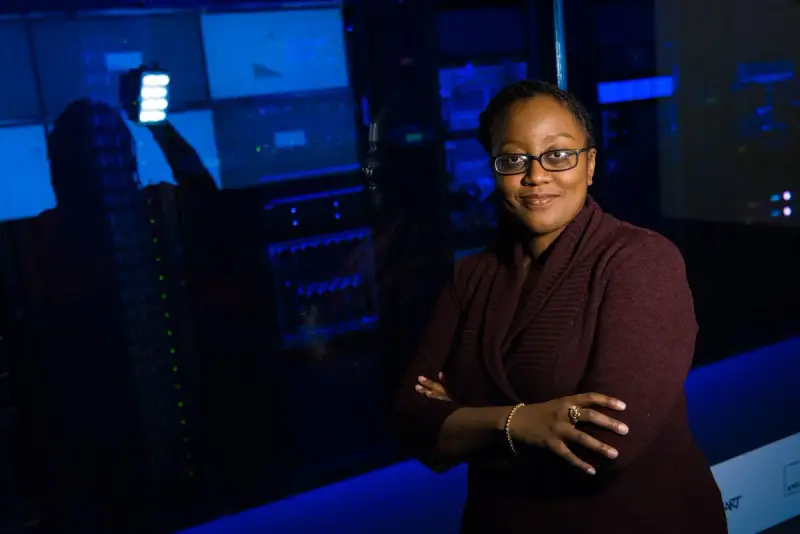 Woman with arms crossed in a data center lit by blue server lights