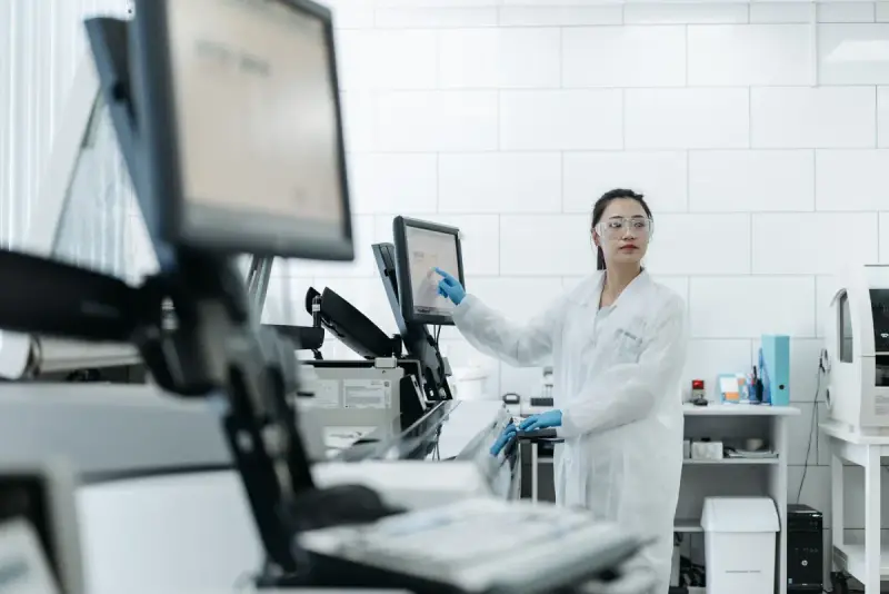 Woman in a laboratory coat working at an analytical instrument and monitor