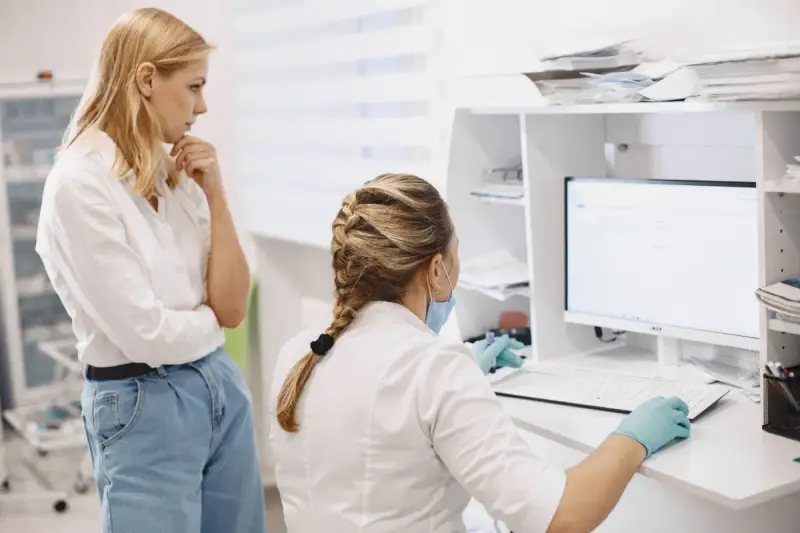 Two women in medical coats reviewing a computer screen together