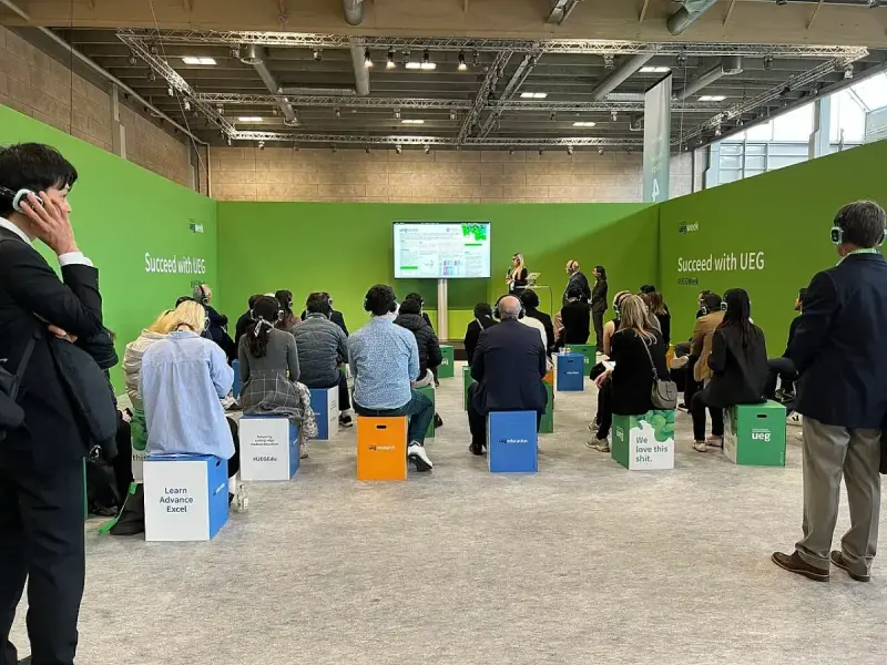Female speaker presenting research to delegates at a UEG Week 2023 poster session