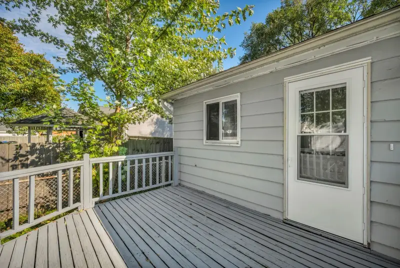 Grey painted deck with a white railing and lattice skirting beside a ranch house door