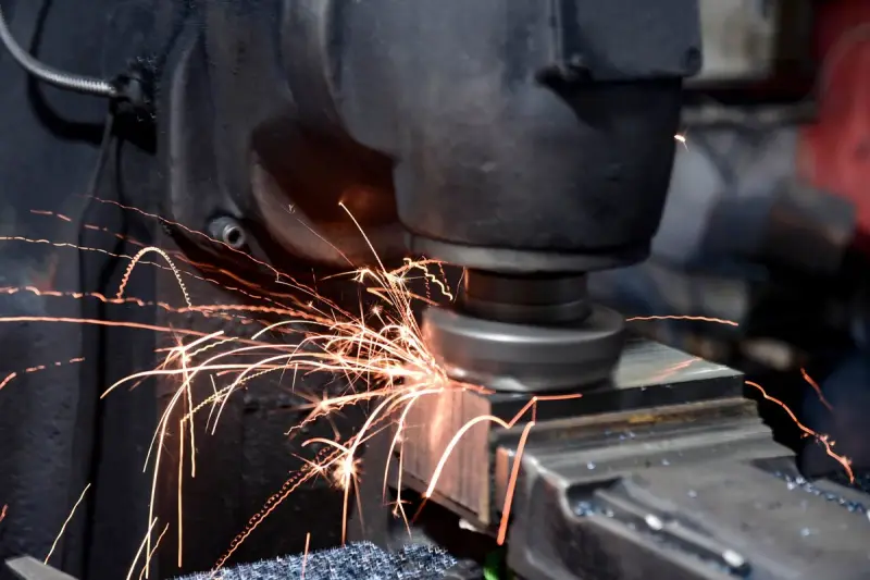 Sparks streaming from a grinding wheel as it dresses a steel block