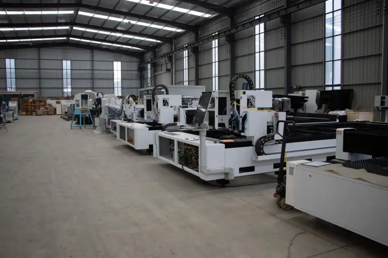 Rows of white industrial cutting machines lined up in a bright, high-ceilinged factory hall