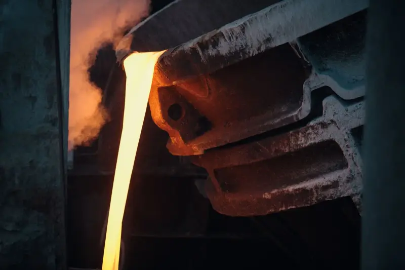 Molten metal pouring from a ladle inside an industrial foundry
