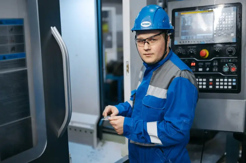 Engineer in safety gear working at the controls of a CNC machine