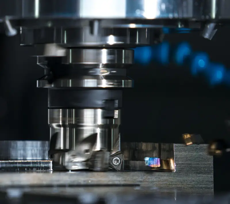 Face mill on a CNC spindle cutting across a steel workpiece