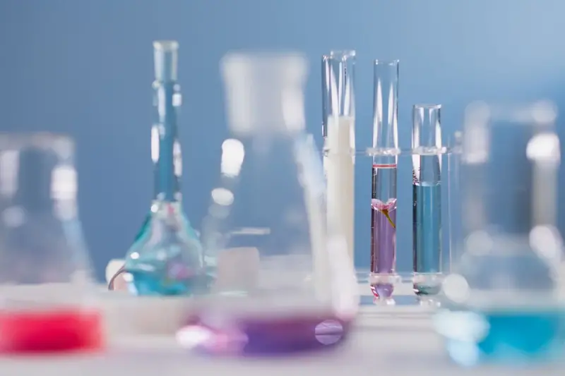 Glass flasks and test tubes holding pink, purple and blue solutions on a lab bench