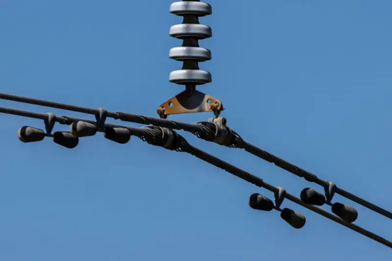 Overhead power line conductors against a blue sky