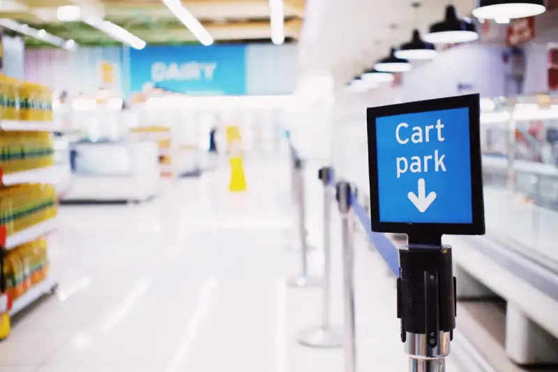 Blue cart park sign in a modern supermarket with blurred aisles behind