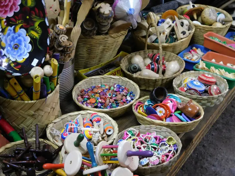 Colorful handmade toys displayed in woven baskets on a market table