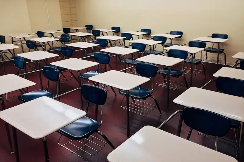 Rows of tablet-arm desks with navy seats in an empty lecture classroom