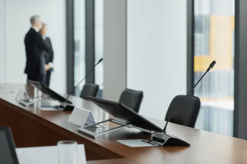 Monitors and microphones on a wooden conference table