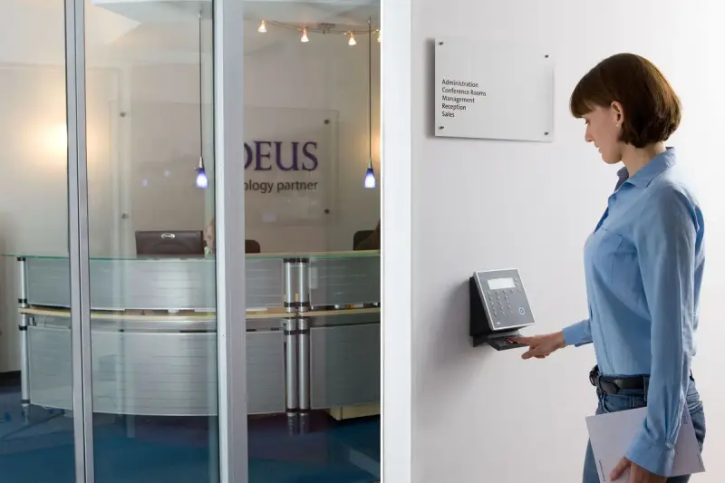 Woman using a fingerprint scanner for door access in an office