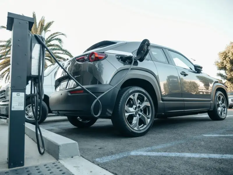Gray electric car parked in an outdoor charging bay in daylight