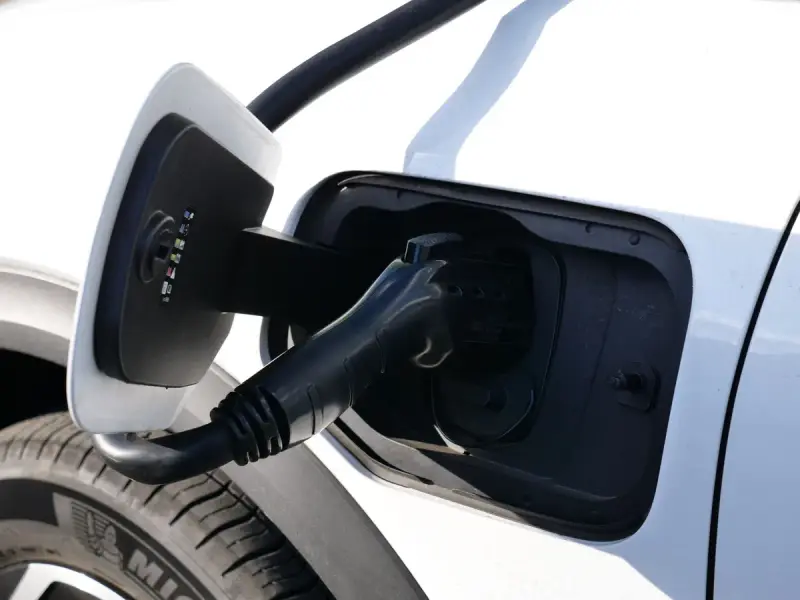 Close-up of a charging connector seated in a car charging port in sunlight