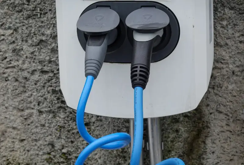 Wall-mounted charging station with two cables in their sockets against a textured wall