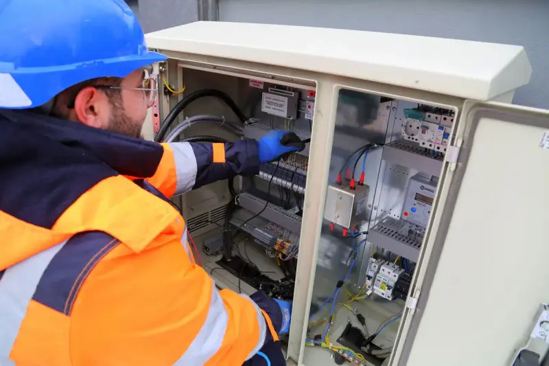 Engineer in safety gear working on an outdoor electrical panel