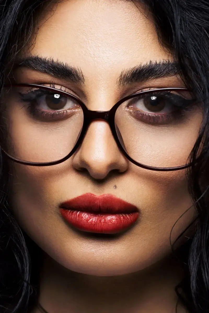 Close-up of a woman in oversized dark eyeglasses with red lipstick