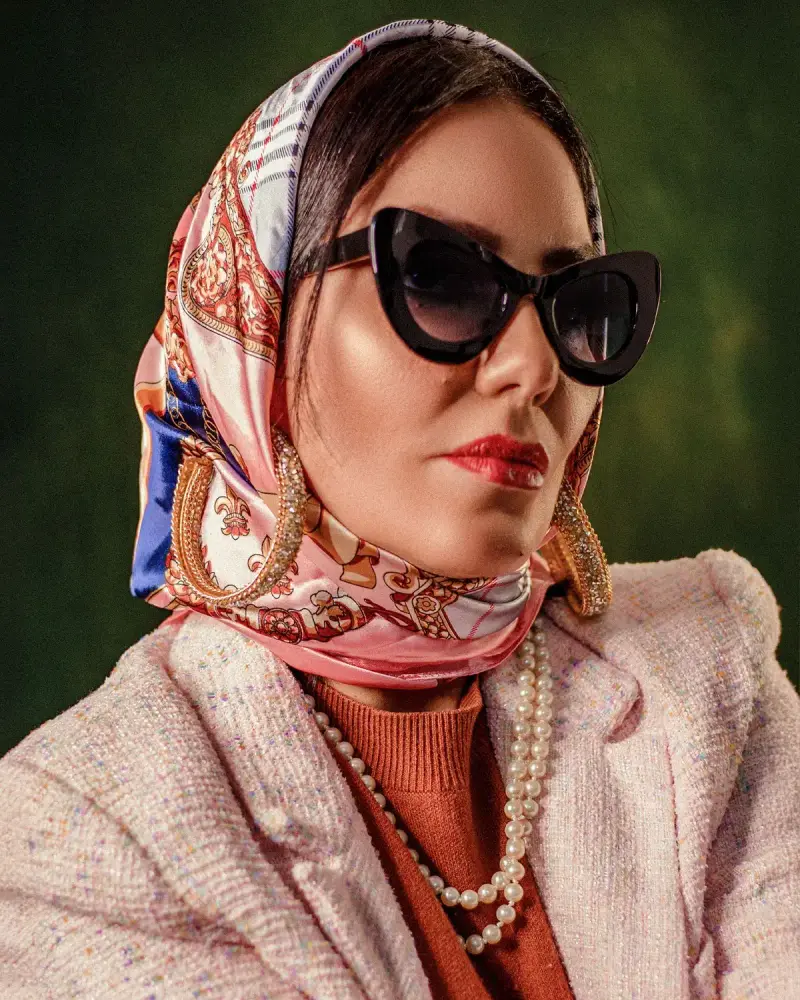Woman in cat-eye sunglasses, silk headscarf and pearls, vintage luxury style