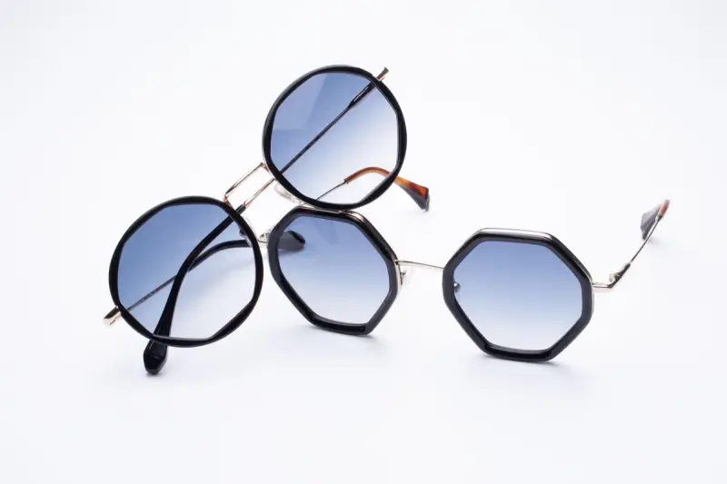 Round and geometric sunglasses with gradient lenses on a white surface