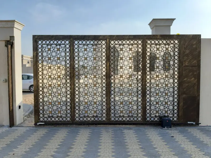 Ornamental metal sliding driveway gate with a gate operator motor at its base
