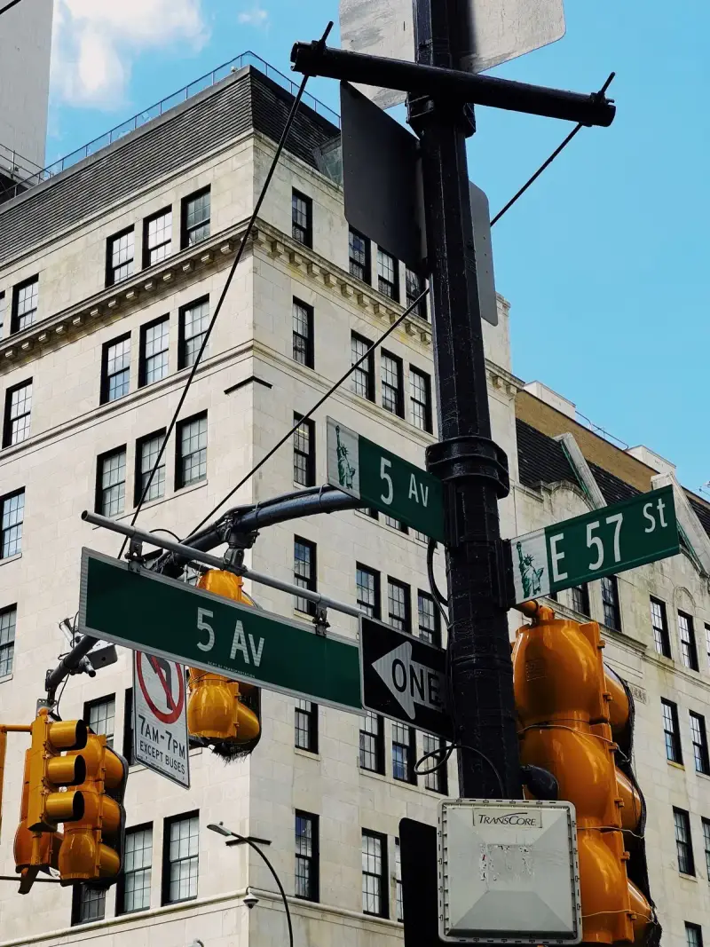 Street signs at Fifth Avenue and East 57th Street against office buildings