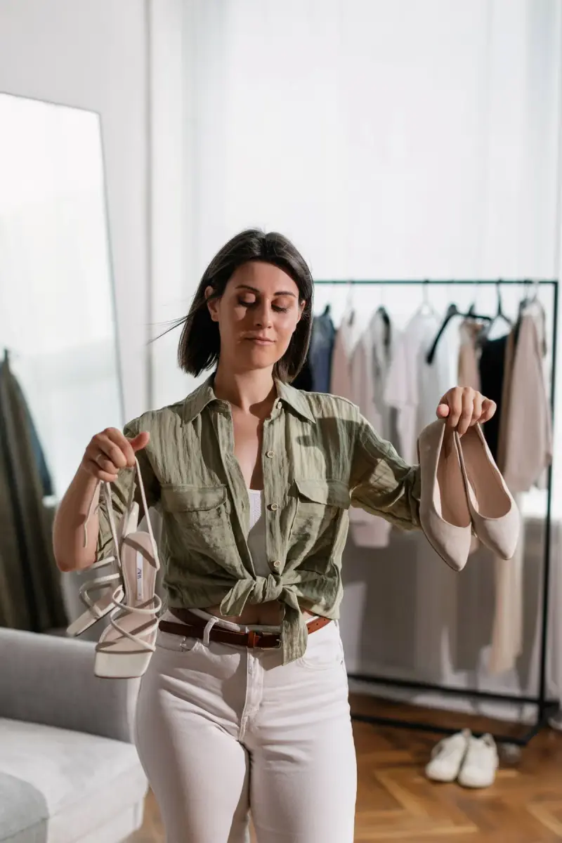 Woman holding up two pairs of shoes while choosing between them