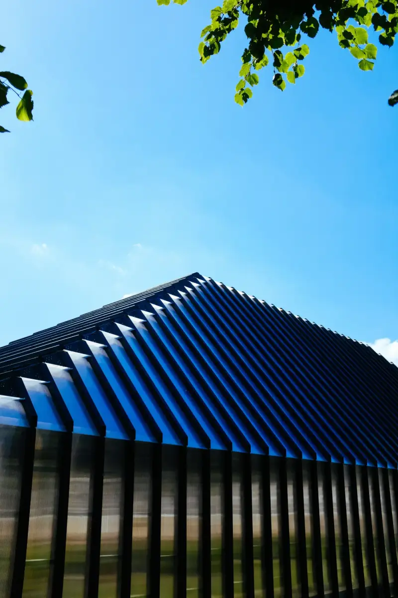 A contemporary building with a blue metal roof beneath a clear sky.