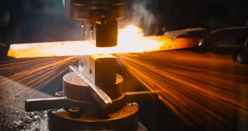 Red-hot steel bar under a forging press with sparks spraying outward