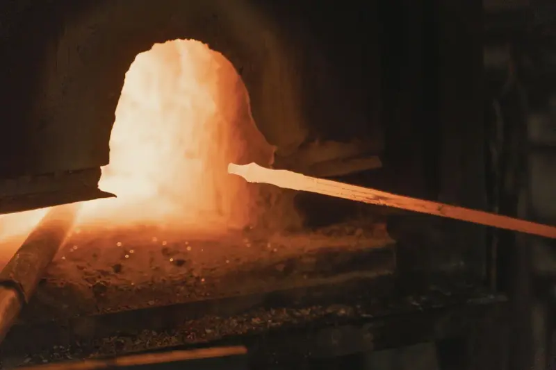 Steel bar heating to forging temperature inside a white-hot gas forge