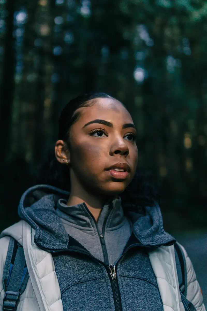 Woman in a gray fleece and white puffer vest in a forest