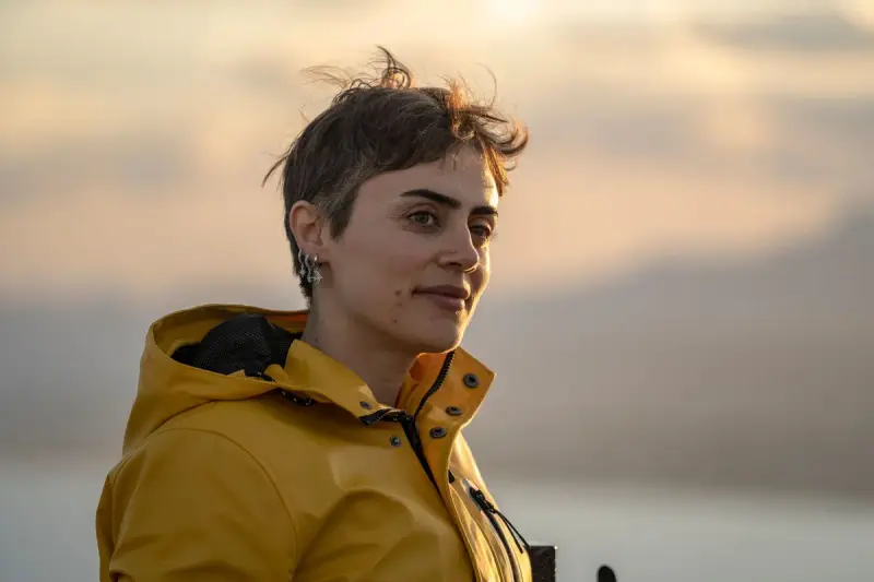 Woman with short hair in a yellow rain jacket at sunset