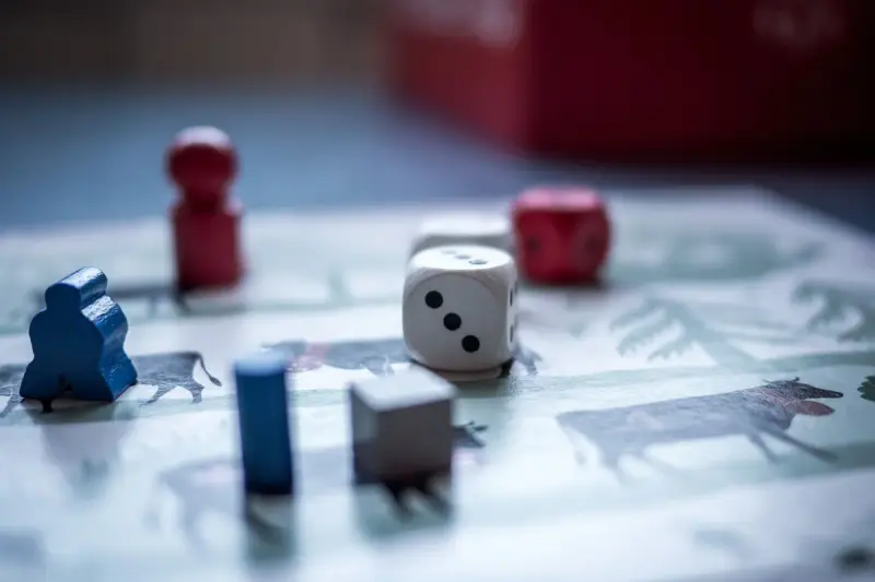 Wooden pawns, white dice and small tokens on an illustrated game board