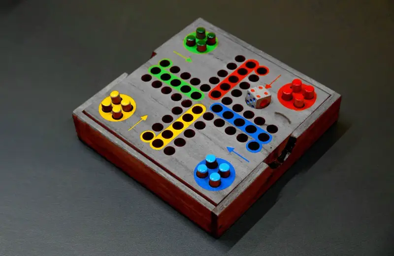 Handmade wooden race game with red, green, blue and yellow pegs and a die
