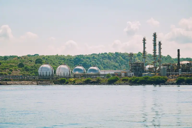 Spherical gas storage tanks and process towers along a wooded waterfront