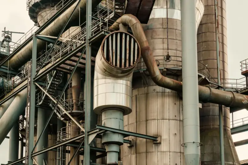 Insulated pipework, ducts and steel stairs on the side of a process tower