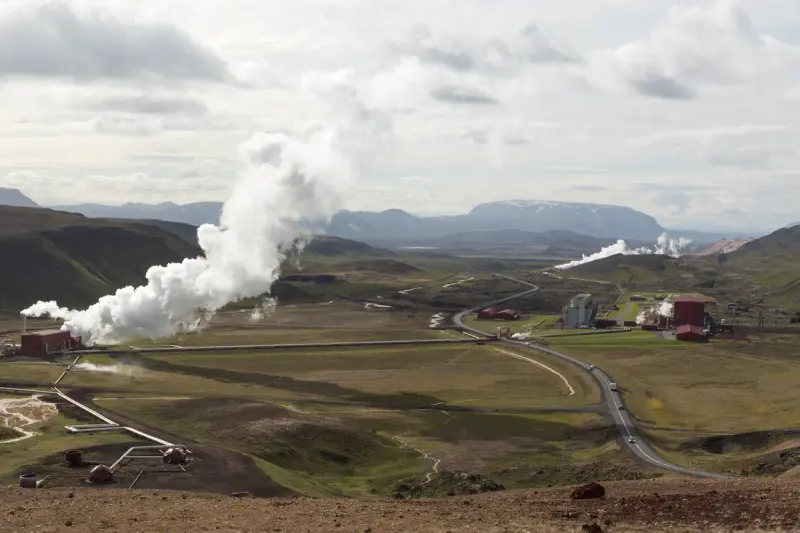 Geothermal power plant and steam pipelines in a volcanic landscape seen from above