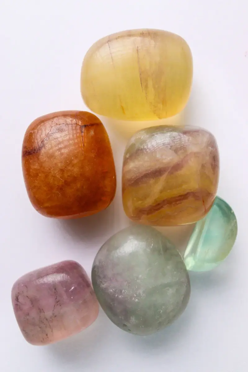Polished fluorite tumbled stones in yellow, purple, green and orange on white