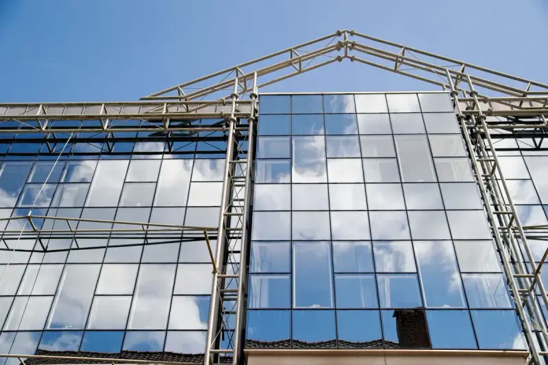 Angular glass and steel facade with a cantilevered upper volume against a cloudy sky