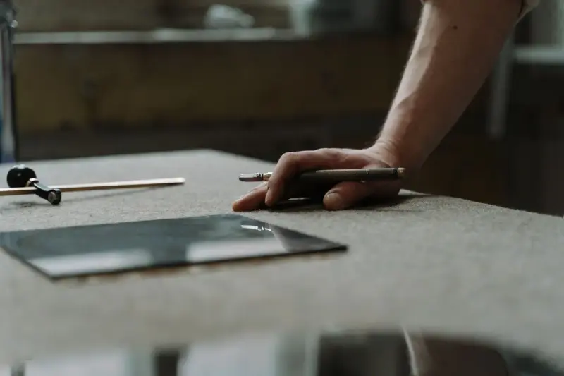 Glass cutter, ruler and a cut glass pane on a felt-covered work table