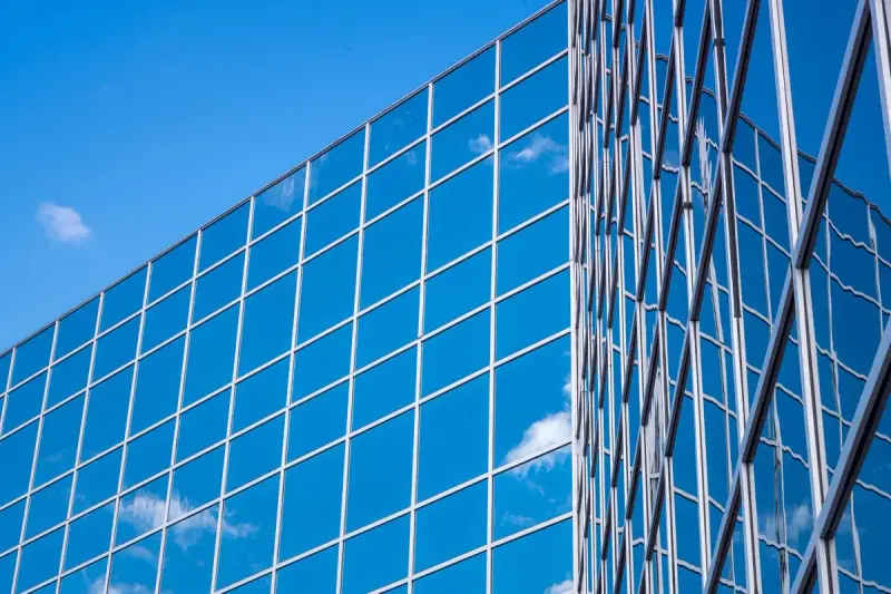 Blue reflective glass curtain wall grid on two building faces under a clear sky