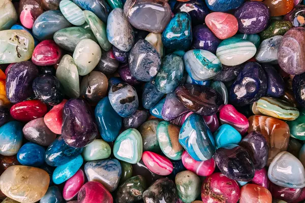A colorful spread of polished tumbled gemstones in red, green, blue and cream