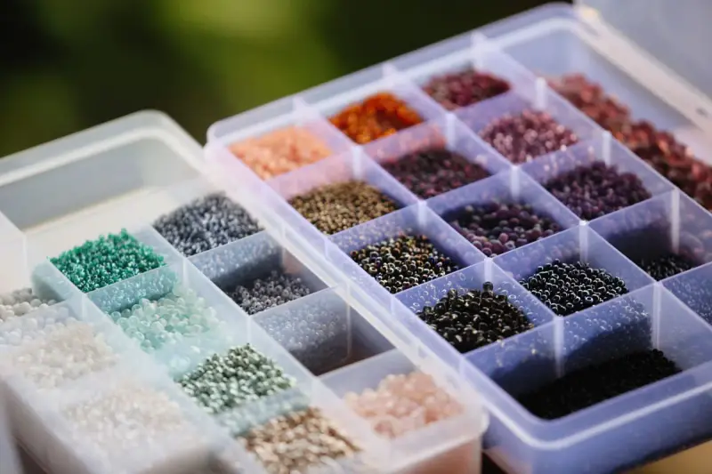 Clear organizer trays of colorful seed beads sorted by color