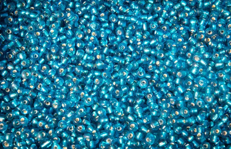 Loose shiny turquoise glass seed beads filling the frame