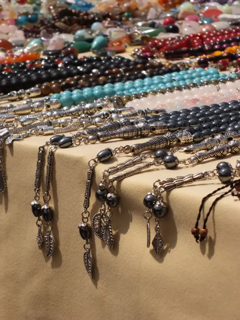 Silver pendant necklaces and turquoise and onyx bead strands laid on a vendor table
