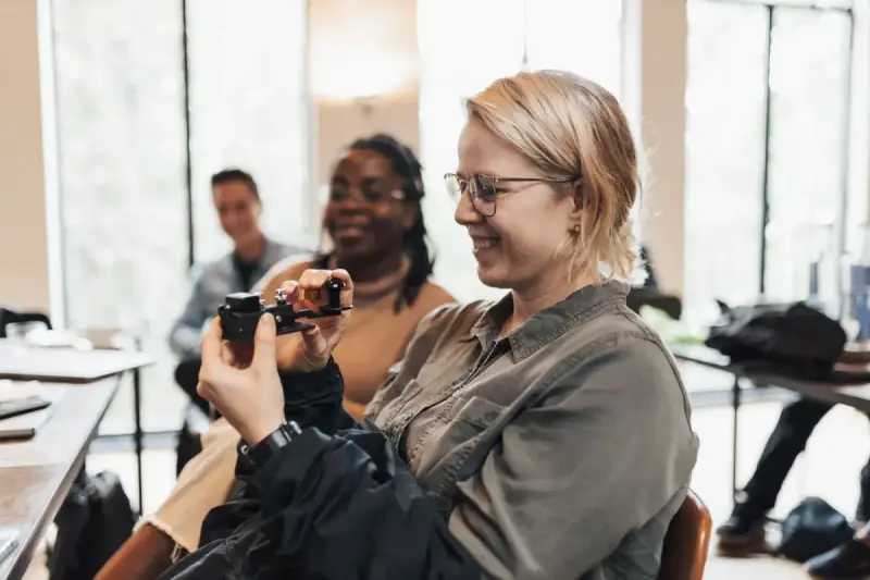 Participants examining a handheld device in a workshop; technology interaction reference.