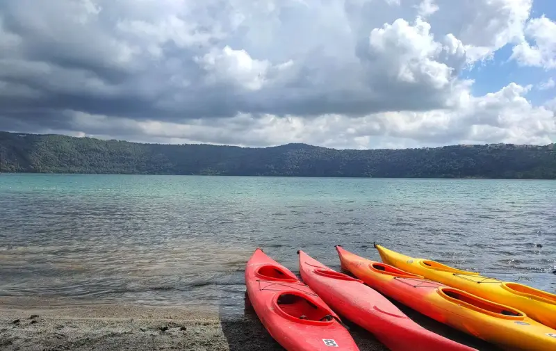Red and yellow kayaks resting on a lakeshore under a cloudy sky