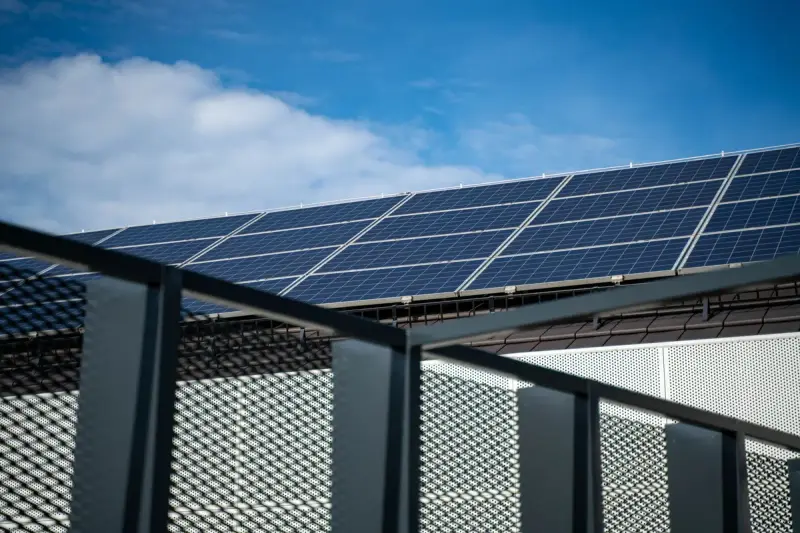 Rows of blue solar panels on a rooftop against a clear sky