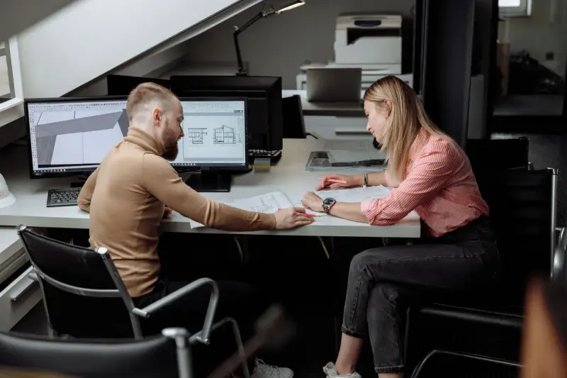 Two architects discussing project drawings in a bright contemporary office