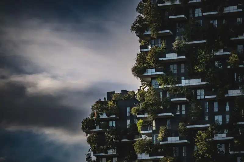 High-rise facade covered in trees and plants on every balcony against a dramatic sky